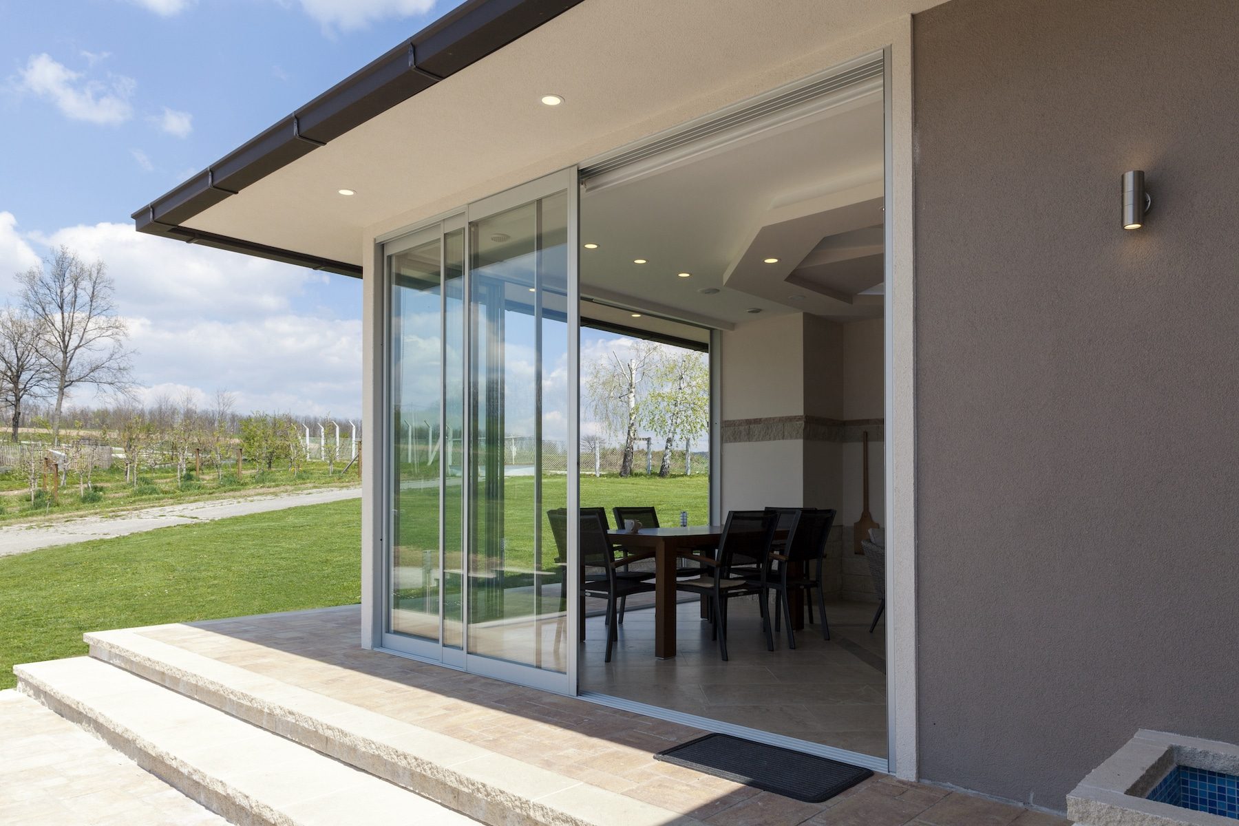 silver sliding patio doors open looking to a lawn
