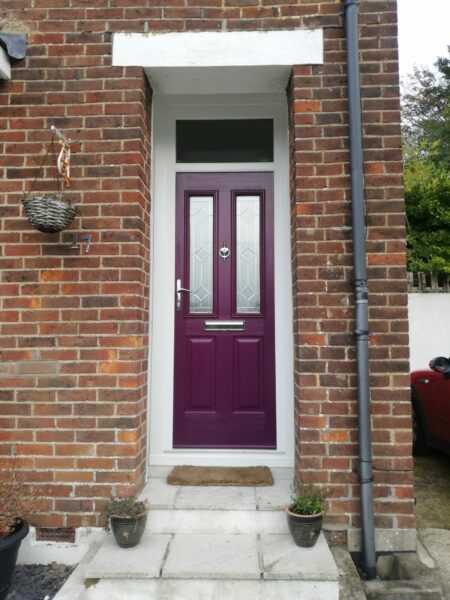 burgundy composite front door with white frame in an end terrace house